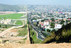 A small fence separates densely populated Tijuana, Mexico, right, from the United States in the Border Patrol’s San Diego Sector.  Construction is underway to extend a secondary fence over the top of this hill and eventually to the Pacific Ocean.